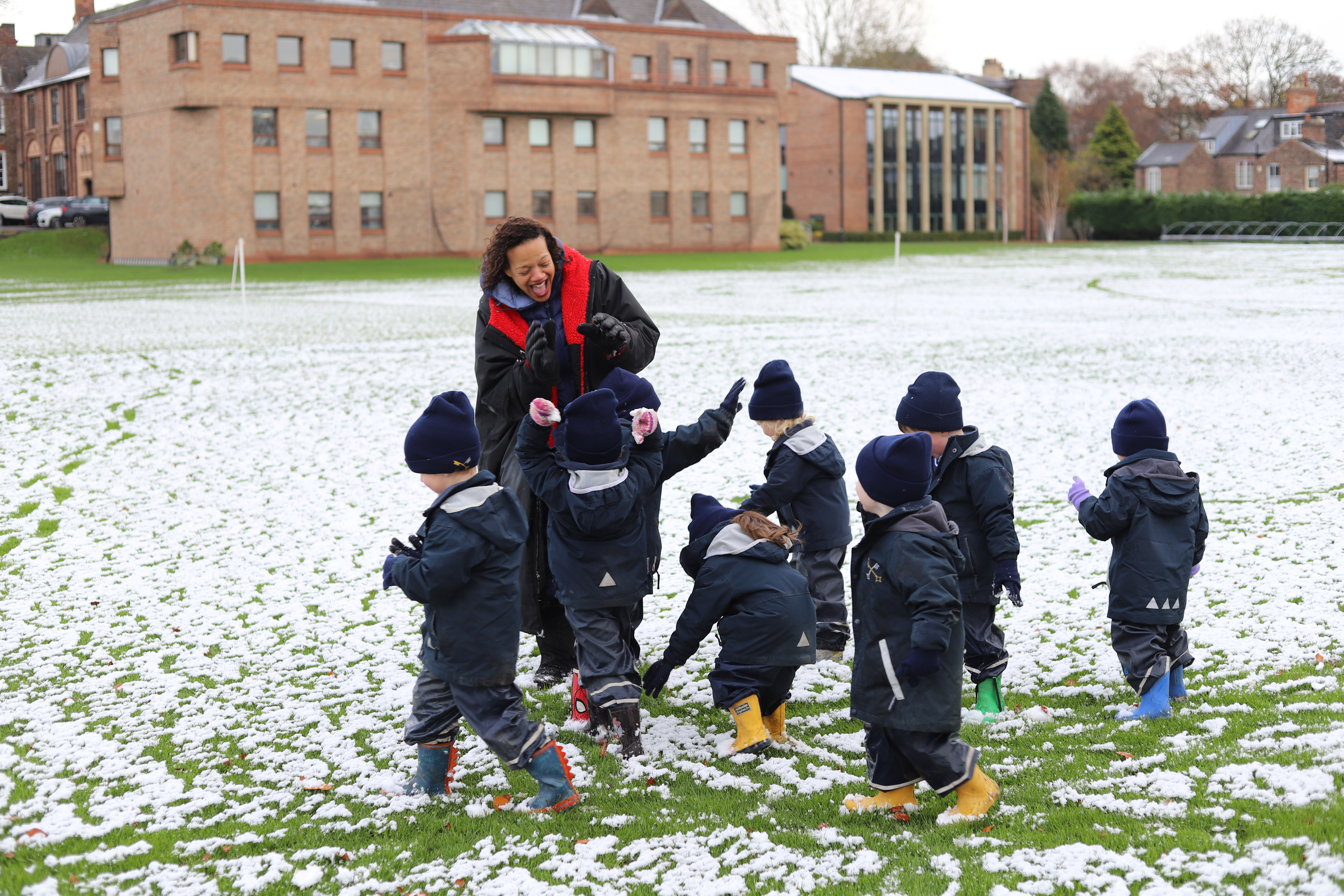 children playing in snow with teacher