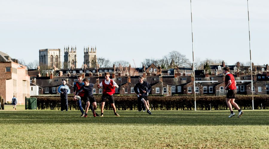 Photo of sports filed with students playing rugby